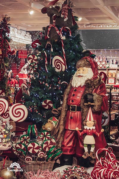 Grand père Noël près du sapin décoré de décorations gourmandes